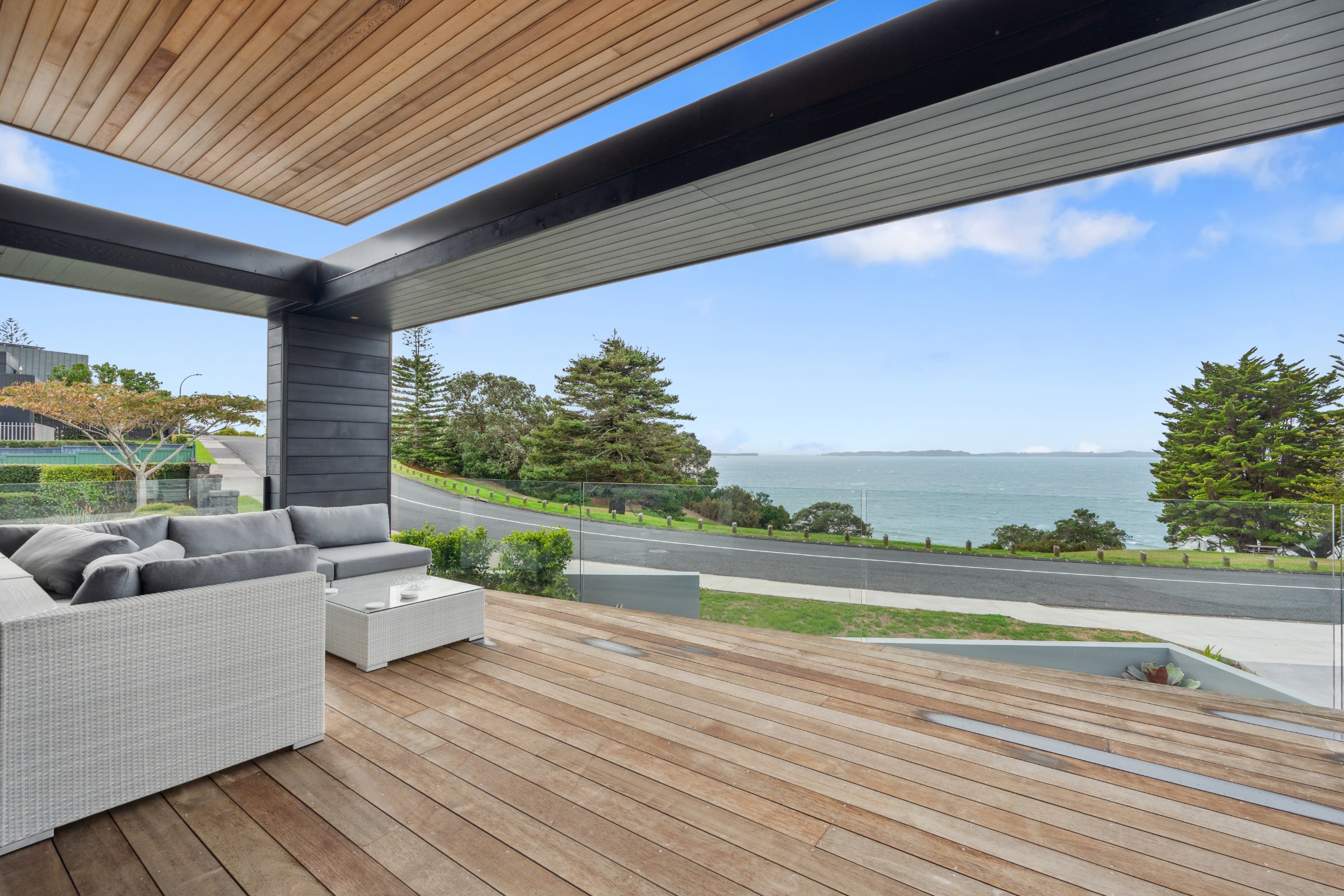 Covered deck with outdoor seating and a sea view in Auckland