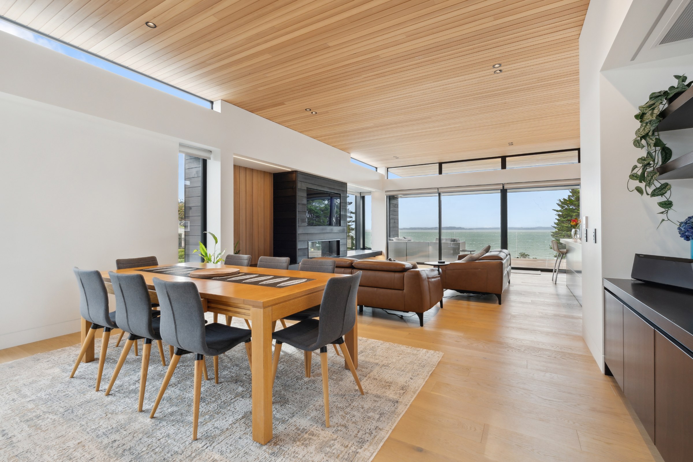 Dining room with a timber ceiling and sea view in Auckland