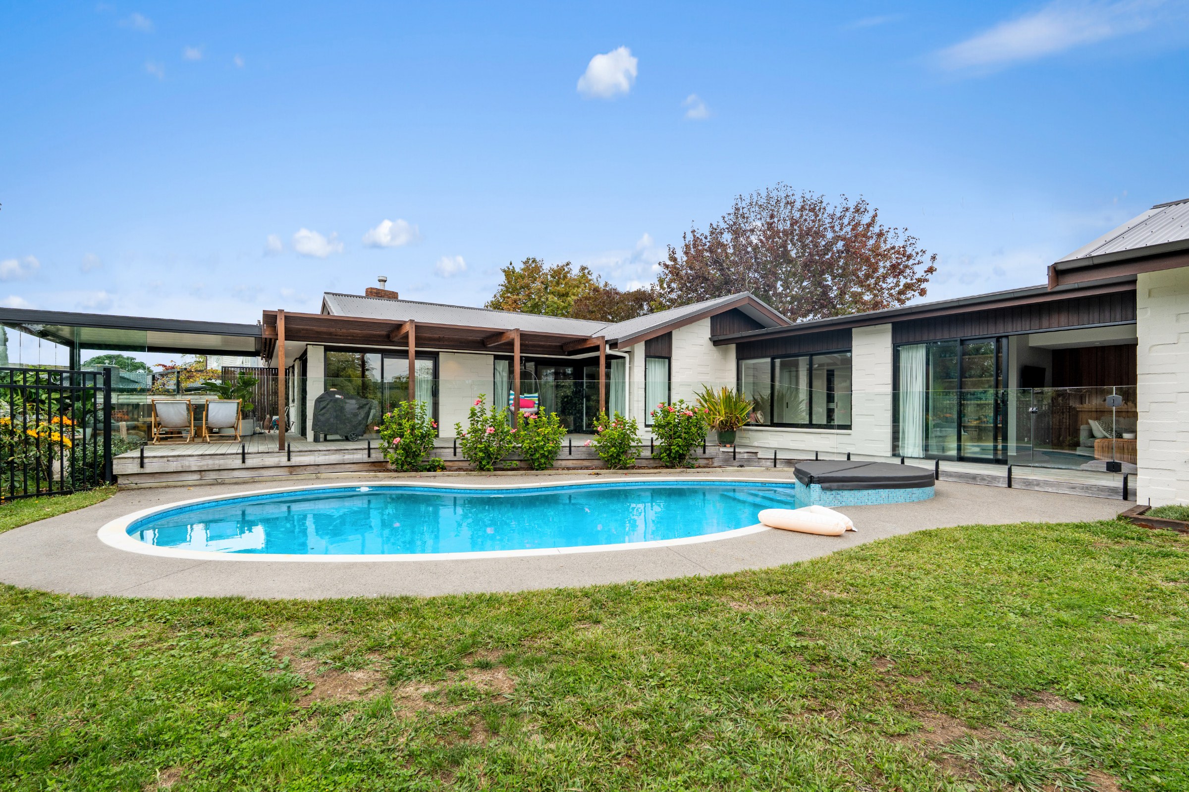 Pool and lawn beside a single-level home in Auckland