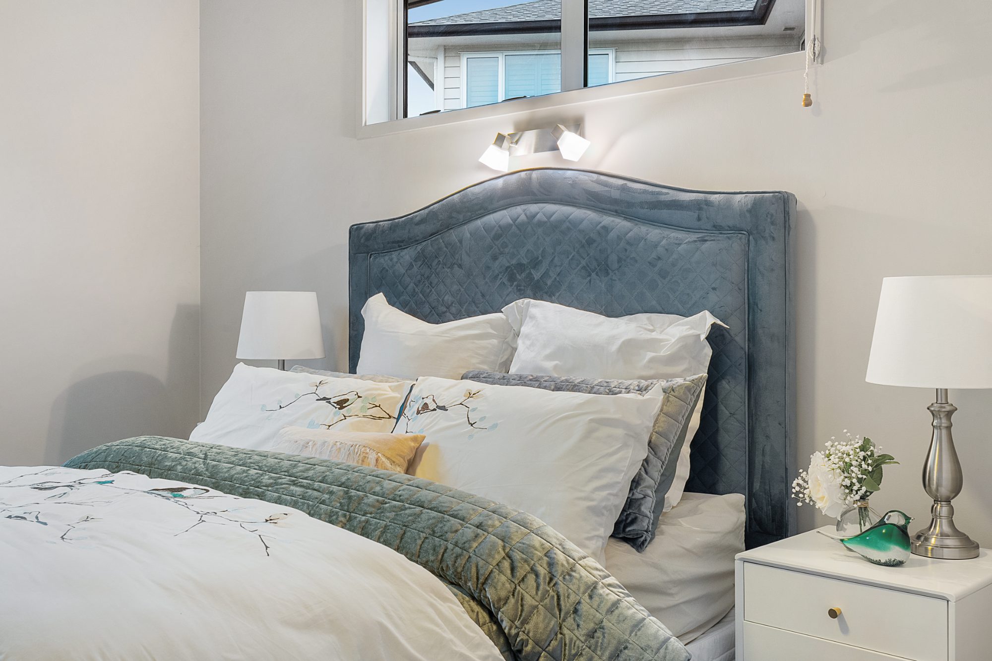 Bedroom with upholstered headboard in a Karaka home