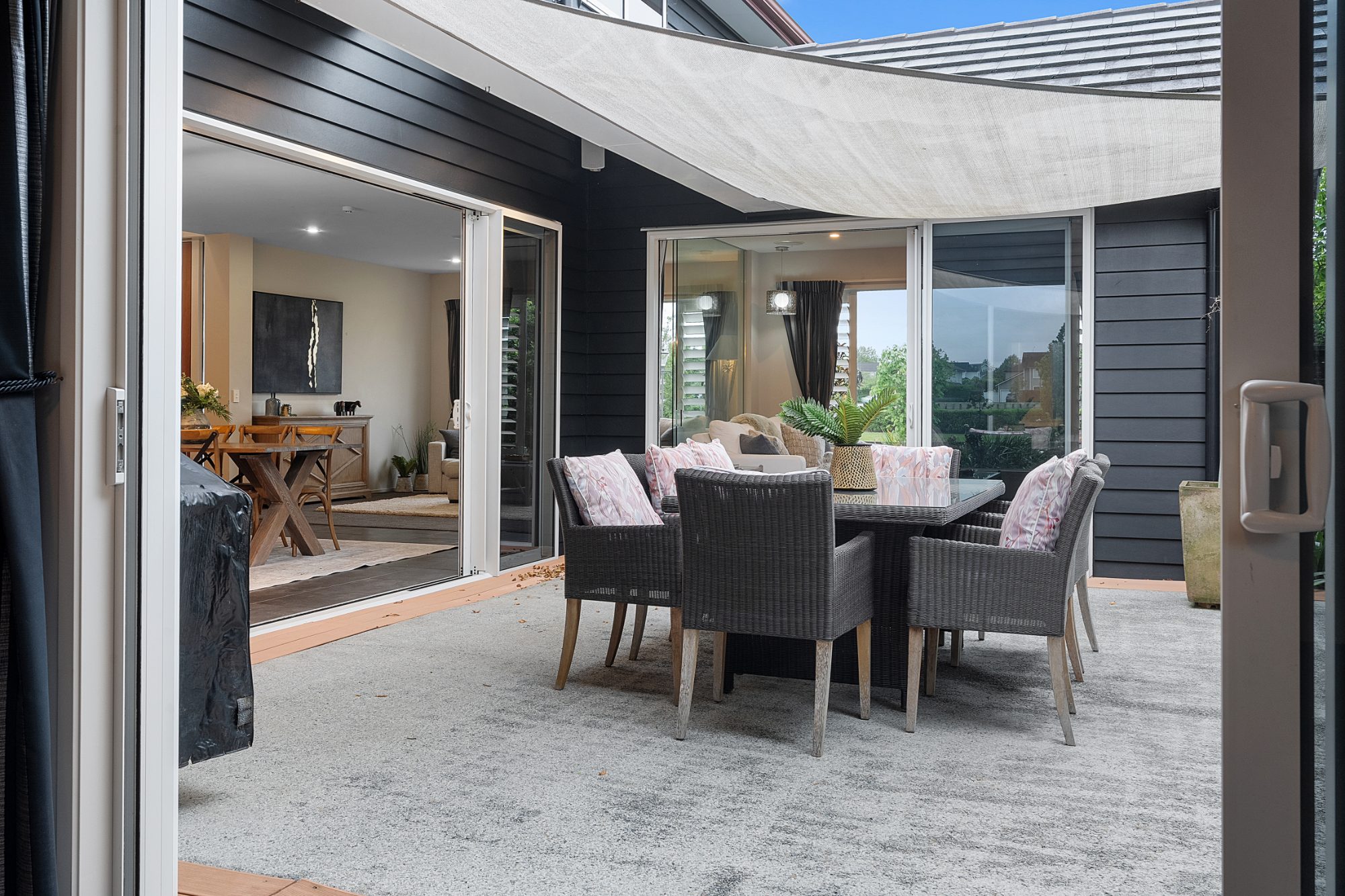 Covered patio with dining table and shade sail at a Karaka home