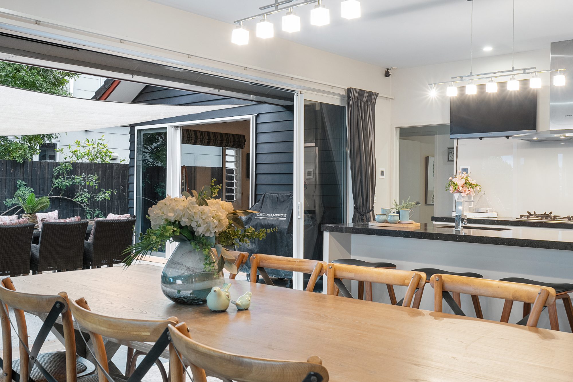 Open-plan kitchen and dining flowing to the patio in a Karaka home