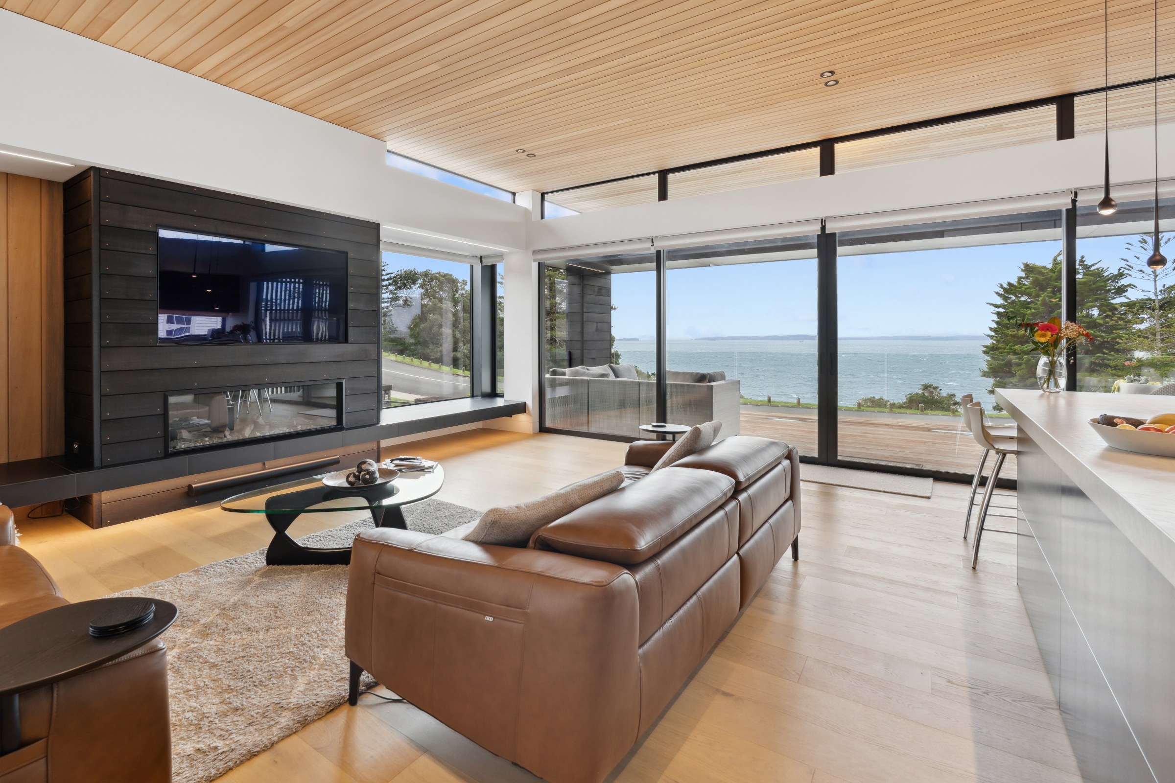 Living room with a fireplace, timber ceiling and sea view in Mission Bay