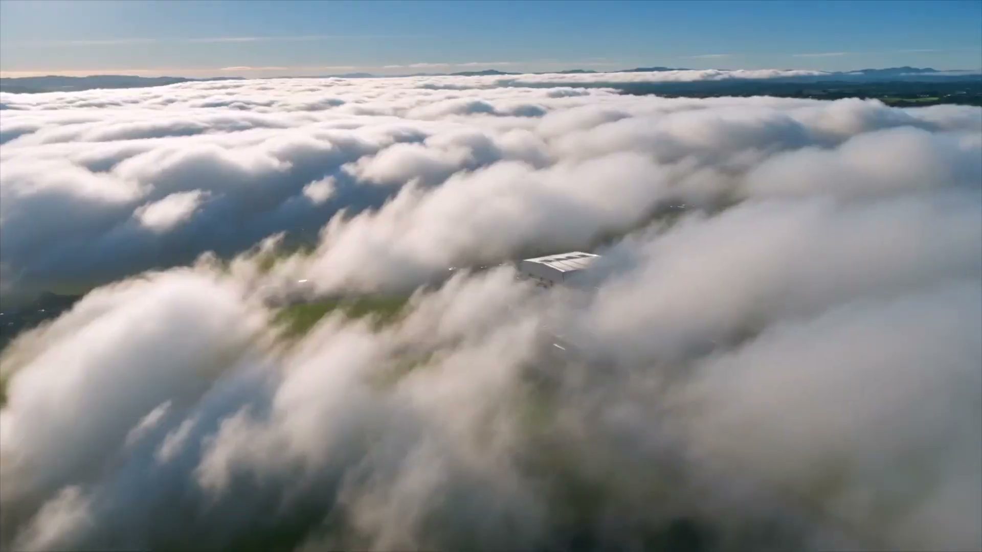 Aerial view above the clouds at the start of a commercial property film in Māngere